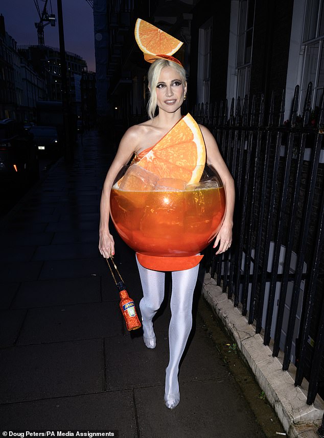 Pixie Lott goes all out for Halloween by dressing up as an Aperol Spritz as she arrives at exclusive Mayfair members club for lavish bash