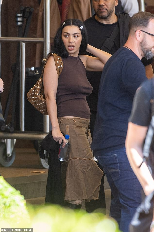 Charli XCX looks effortlessly cool as she steps out of Melbourne hotel braless in brown tank top